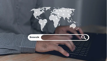 Digital marketer working on laptop with global search interface, symbolizing improved search visibility.